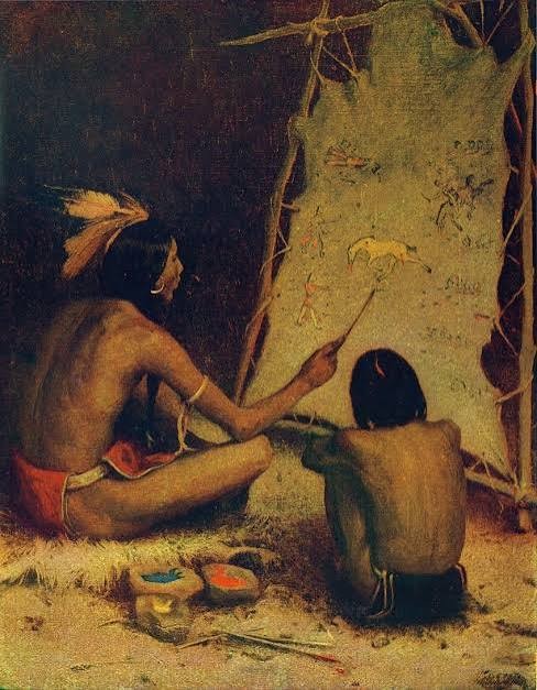 An elder and a child painting figures on a cave wall together